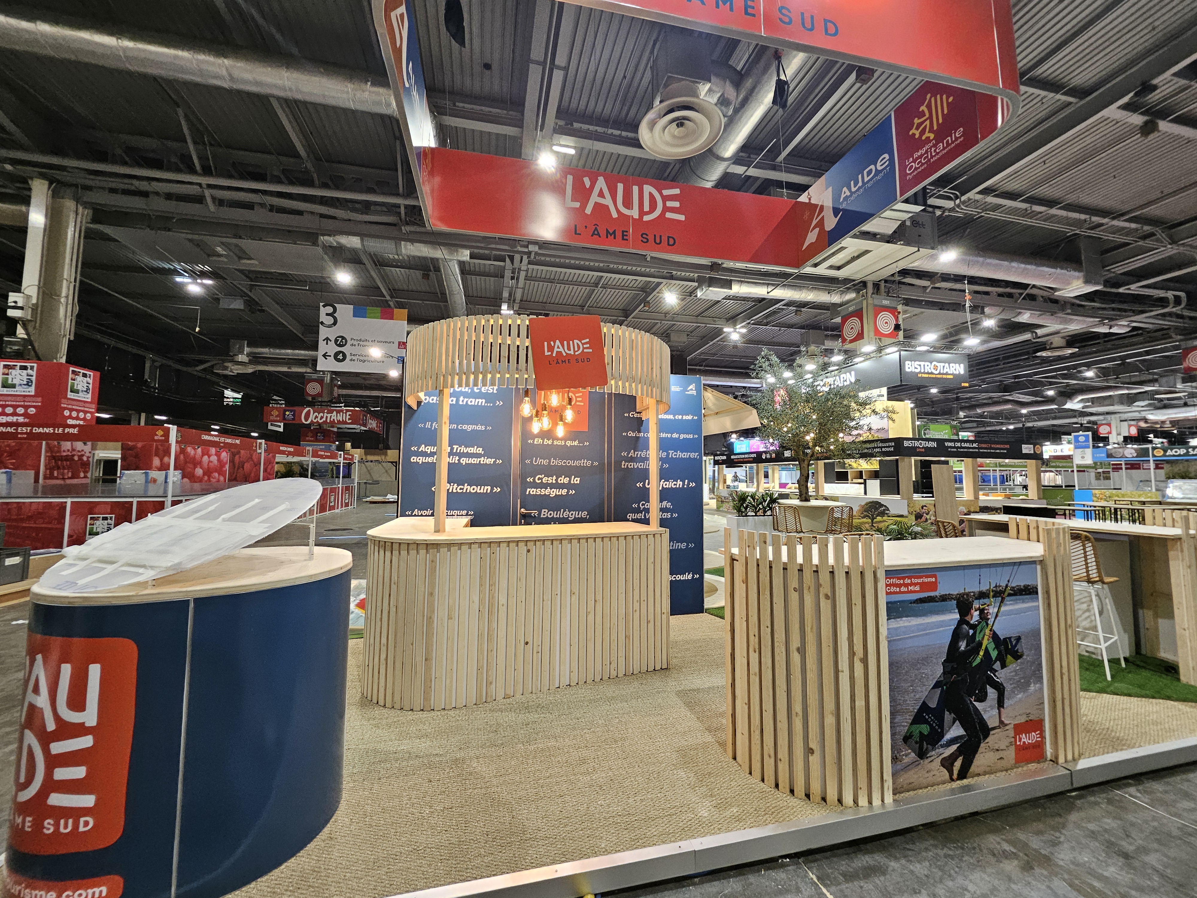 Stand de l'Aude au SIA à Paris avec uen enseigne haute, desk en bois et sol en jonc de mer