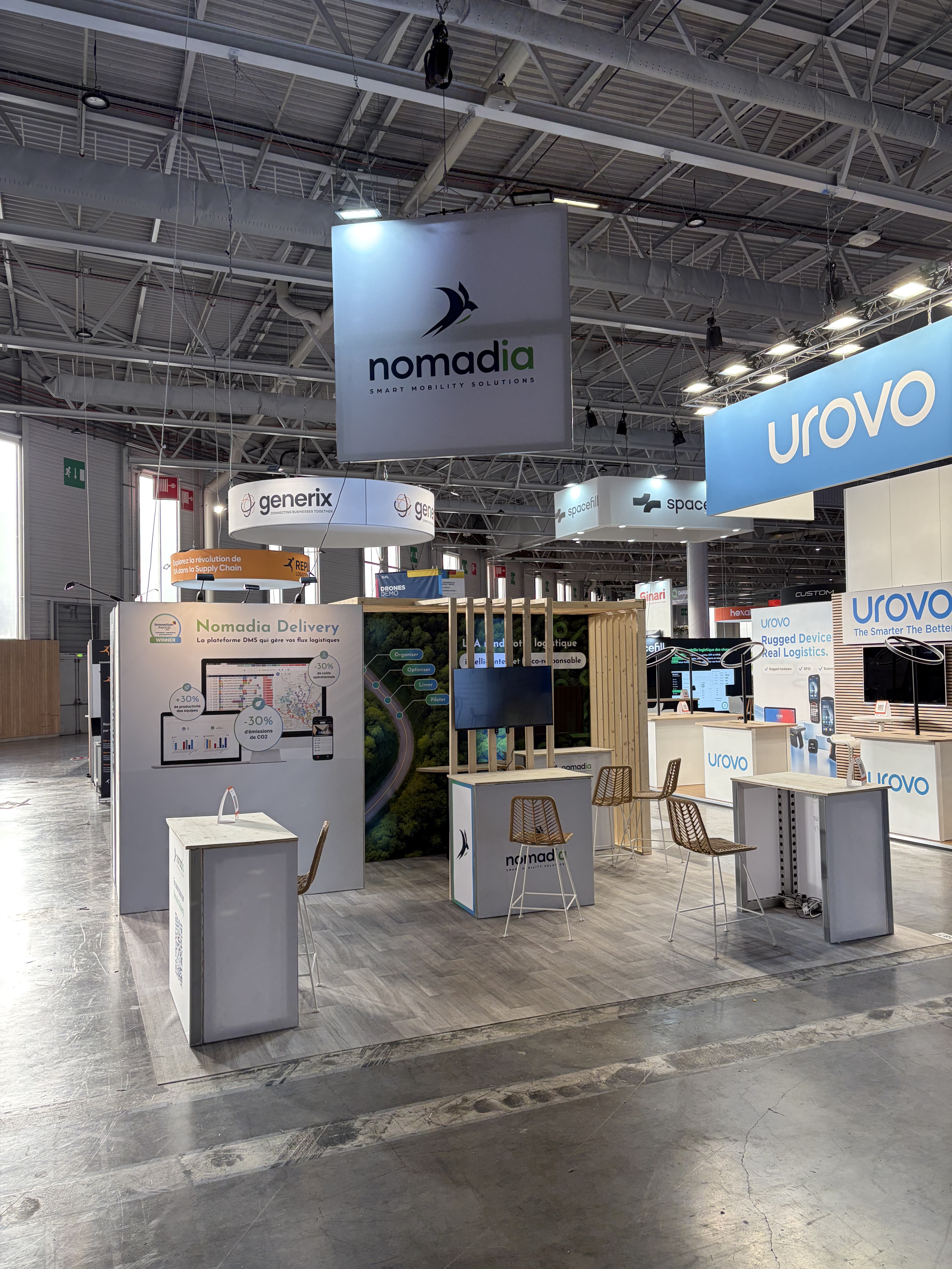 stand de Nomadia au SITL 2026 à Paris avec plusieurs desks d'accueil et lino effet parquet
